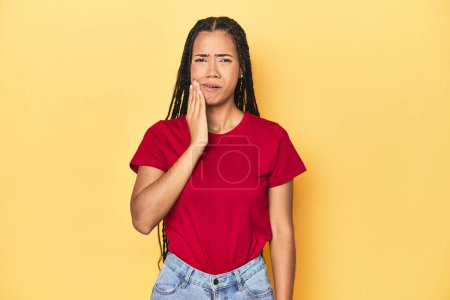 Téléchargez les photos : Jeune femme indonésienne sur fond de studio jaune ayant une forte douleur aux dents, douleur molaire. - en image libre de droit