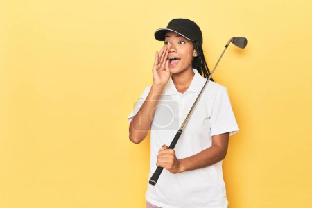 Photo for Indonesian female golfer on yellow backdrop shouting and holding palm near opened mouth. - Royalty Free Image