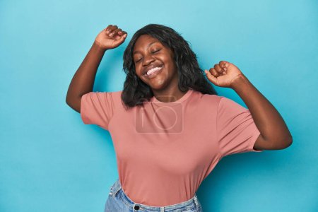 Téléchargez les photos : Jeune femme courbée afro-américaine célébrant un jour spécial, saute et lève les bras avec énergie. - en image libre de droit