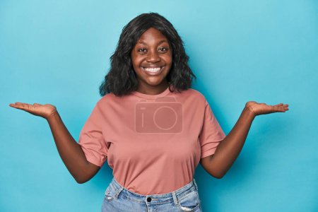 Foto de Joven africana americana curvilínea mujer hace escala con los brazos, se siente feliz y seguro. - Imagen libre de derechos