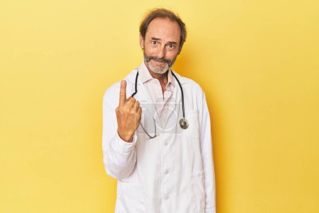 Photo for Doctor with stethoscope in yellow studio pointing with finger at you as if inviting come closer. - Royalty Free Image