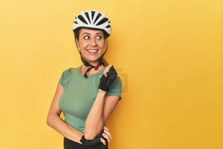 Photo for Portrait of beautiful adult woman points with thumb finger away, laughing and carefree. - Royalty Free Image