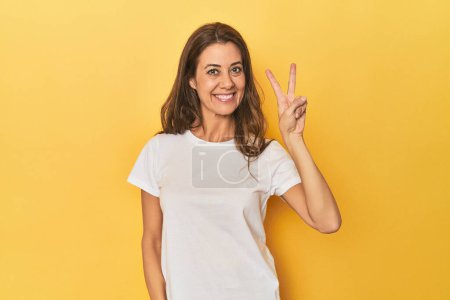 Téléchargez les photos : Portrait de belle femme adulte joyeuse et insouciante montrant un symbole de paix avec les doigts. - en image libre de droit