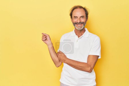 Téléchargez les photos : Caucasien d'âge moyen homme en studio jaune souriant joyeusement pointant avec index loin. - en image libre de droit