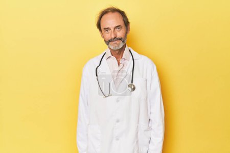 Photo for Doctor with stethoscope in yellow studio happy, smiling and cheerful. - Royalty Free Image