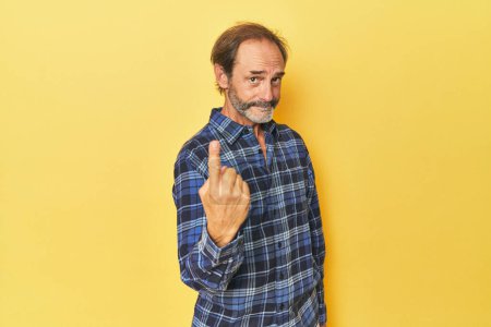 Téléchargez les photos : Caucasien d'âge moyen l'homme dans jaune studio pointant avec doigt à vous comme si inviter venir plus proche. - en image libre de droit