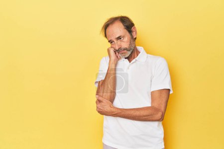 Téléchargez les photos : Blanc d'âge moyen homme dans un studio jaune qui se sent triste et coûteux, en regardant l'espace de copie. - en image libre de droit