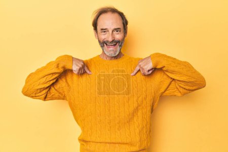 Téléchargez les photos : Blanc homme d'âge moyen en studio jaune surpris pointant du doigt, souriant largement. - en image libre de droit