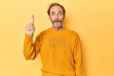 Téléchargez les photos : Homme d'âge moyen caucasien en studio jaune ayant une bonne idée, concept de créativité. - en image libre de droit