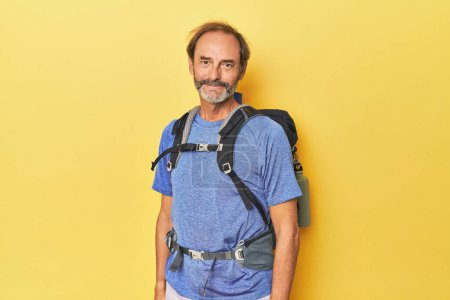 Téléchargez les photos : Randonneur d'âge moyen avec sac à dos en studio heureux, souriant et joyeux. - en image libre de droit
