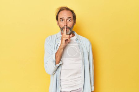 Téléchargez les photos : Homme d'âge moyen caucasien en studio jaune gardant un secret ou demandant le silence. - en image libre de droit