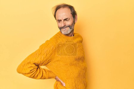 Téléchargez les photos : Caucasien d'âge moyen homme en studio jaune souffrant d'un mal de dos. - en image libre de droit