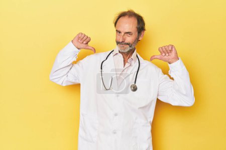 Téléchargez les photos : Médecin avec stéthoscope en studio jaune se sent fier et confiant, exemple à suivre. - en image libre de droit