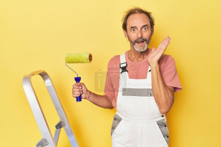 Foto de Hombre pintura amarillo telón de fondo en el estudio sorprendido y sorprendido. - Imagen libre de derechos