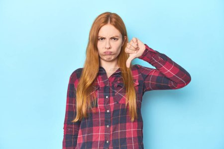Photo for Redhead young woman on blue background showing thumb down, disappointment concept. - Royalty Free Image