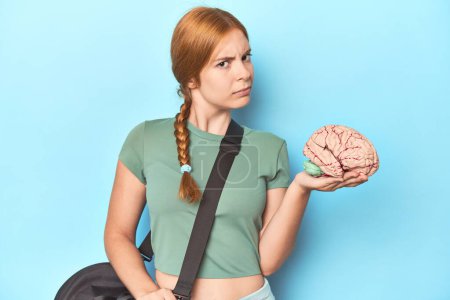 Photo for Redhead athlete holding brain model, showcasing sport's cognitive benefits - Royalty Free Image