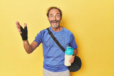 Photo for Gym-goer with protein shake in studio receiving a pleasant surprise, excited and raising hands. - Royalty Free Image