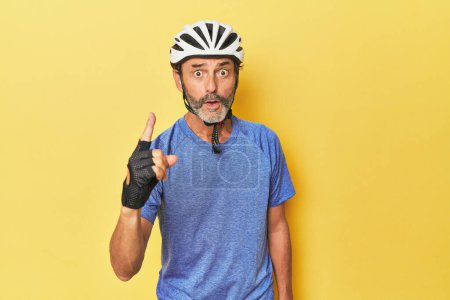 Foto de Ciclista con casco en estudio amarillo teniendo una idea, concepto de inspiración. - Imagen libre de derechos