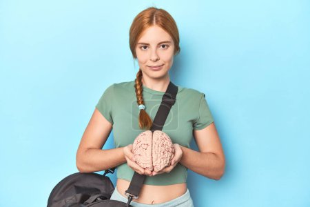Photo for Redhead athlete holding brain model, showcasing sport's cognitive benefits - Royalty Free Image