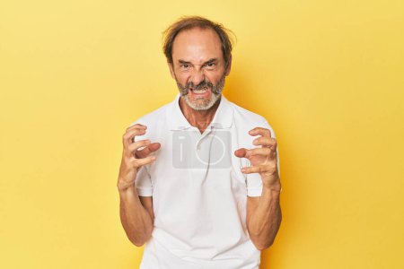 Foto de Caucásico de mediana edad hombre en amarillo estudio molesto gritando con las manos tensas. - Imagen libre de derechos