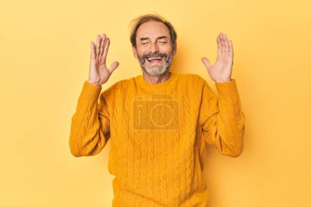 Téléchargez les photos : Homme d'âge moyen caucasien en studio jaune joyeux rire beaucoup. Concept de bonheur. - en image libre de droit
