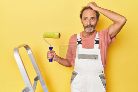 Photo for Man painting yellow backdrop in studio being shocked, she has remembered important meeting. - Royalty Free Image