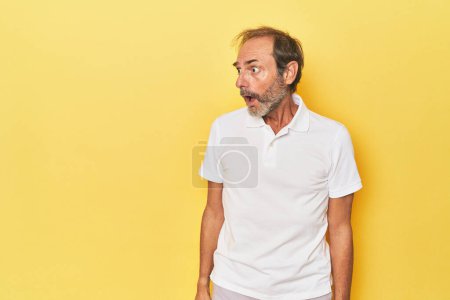 Foto de Caucásico de mediana edad hombre en amarillo estudio siendo sorprendido por algo que ella ha visto. - Imagen libre de derechos
