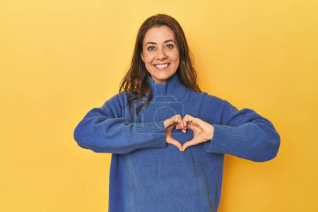 Photo for Portrait of beautiful adult woman smiling and showing a heart shape with hands. - Royalty Free Image