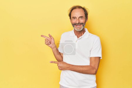 Téléchargez les photos : Caucasien d'âge moyen homme en studio jaune excité pointant avec les index loin. - en image libre de droit
