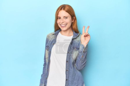 Photo for Redhead young woman on blue background showing number two with fingers. - Royalty Free Image