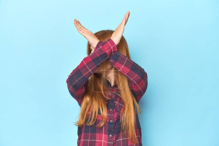 Photo for Redhead young woman on blue background keeping two arms crossed, denial concept. - Royalty Free Image