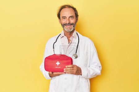 Photo for Doctor with first aid kit in yellow studio - Royalty Free Image