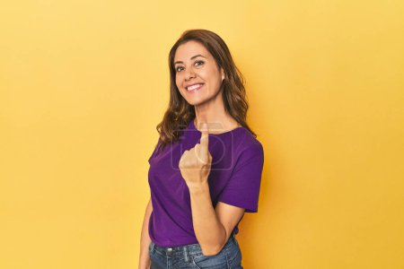 Photo for Portrait of beautiful adult woman pointing with finger at you as if inviting come closer. - Royalty Free Image