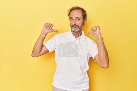 Photo for Caucasian middle-aged man in yellow studio feels proud and self confident, example to follow. - Royalty Free Image