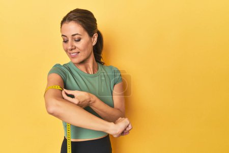 Photo for Portrait of beautiful adult woman in sportswear on yellow background - Royalty Free Image