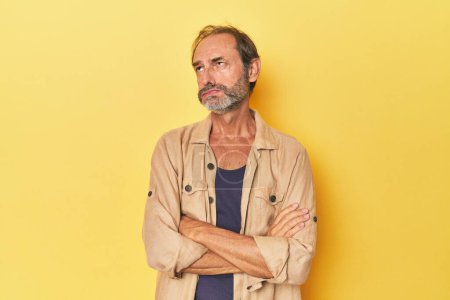 Photo for Caucasian middle-aged man in yellow studio tired of a repetitive task. - Royalty Free Image