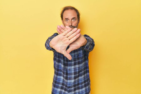 Téléchargez les photos : Caucasien d'âge moyen homme en studio jaune faire un geste de déni - en image libre de droit