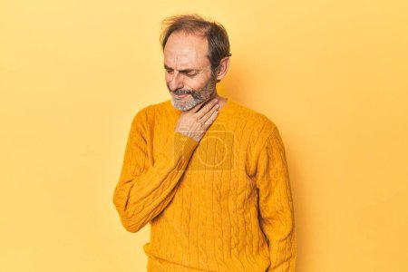Téléchargez les photos : Homme d'âge moyen caucasien en studio jaune souffre de douleur à la gorge due à un virus ou une infection. - en image libre de droit