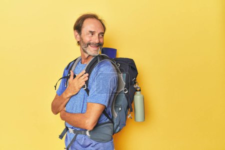 Téléchargez les photos : Randonneur d'âge moyen avec sac à dos en studio regarde de côté souriant, joyeux et agréable. - en image libre de droit