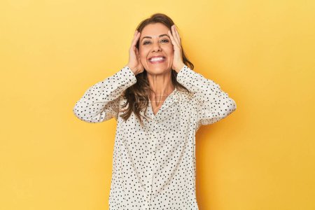 Photo for Portrait of adult woman laughs joyfully keeping hands on head. Happiness concept. - Royalty Free Image
