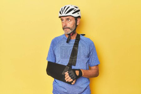 Téléchargez les photos : Cycliste blessé portant fronde semble triste - en image libre de droit