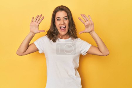 Photo for Portrait of adult woman receiving a pleasant surprise, excited and raising hands. - Royalty Free Image