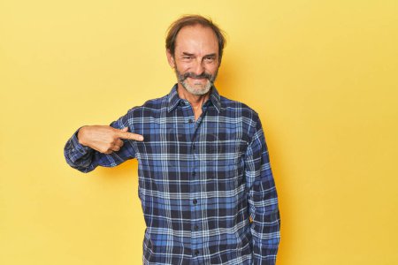 Téléchargez les photos : Homme d'âge moyen caucasien en studio jaune personne pointant à la main vers un espace de copie chemise, fier et confiant - en image libre de droit