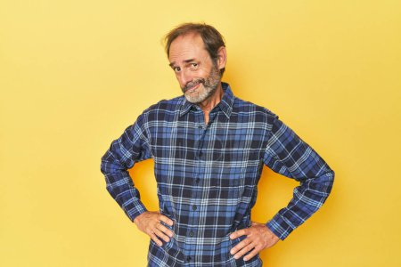 Photo for Caucasian middle-aged man in yellow studio confused, feels doubtful and unsure. - Royalty Free Image