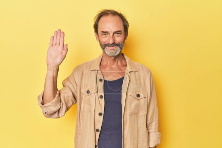 Téléchargez les photos : Blanc homme d'âge moyen en studio jaune souriant gai montrant numéro cinq avec les doigts. - en image libre de droit