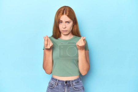 Photo for Redhead young woman on blue background showing that she has no money. - Royalty Free Image