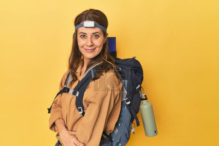 Photo for Portrait of beautiful adult woman with hiking backpack and head lamp on yellow background - Royalty Free Image