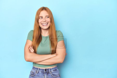 Photo for Redhead young woman on blue background smiling confident with crossed arms. - Royalty Free Image