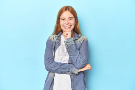 Photo for Redhead young woman on blue background smiling happy and confident, touching chin with hand. - Royalty Free Image