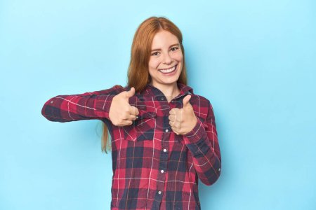 Photo for Redhead young woman on blue background raising both thumbs up, smiling and confident. - Royalty Free Image